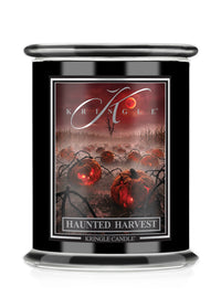 A Kringle Candle jar candle with a black container and a Halloween-themed label reading 'Haunted Harvest.' The label shows glowing red pumpkins, dark vines, and a red sky with the Kringle logo.