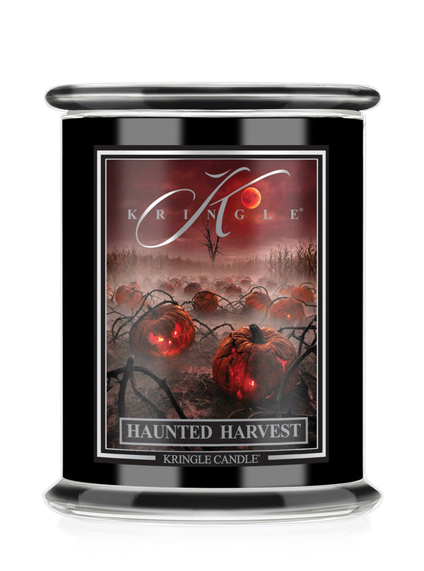 A Kringle Candle jar candle with a black container and a Halloween-themed label reading 'Haunted Harvest.' The label shows glowing red pumpkins, dark vines, and a red sky with the Kringle logo.