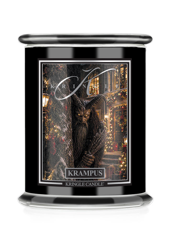 A Kringle Candle Halloween jar with a black glass body, featuring a detailed label of a hairy creature in a festive town scene, labeled 'Krampus'.