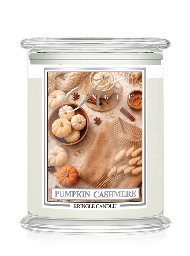 Kringle Candle with a label featuring small pumpkins, cinnamon and sweater on a white background