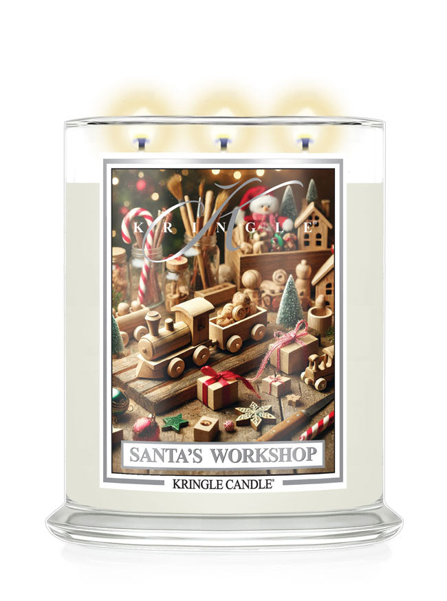 A Kringle Candle jar candle with a lit wick and warm glow, featuring a festive Christmas-themed label reading 'Santa's Workshop' on a white background.