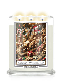 A Kringle Candle jar candle with a lit wick and warm glow, featuring a festive Christmas-themed label reading 'Santa's Workshop' on a white background.