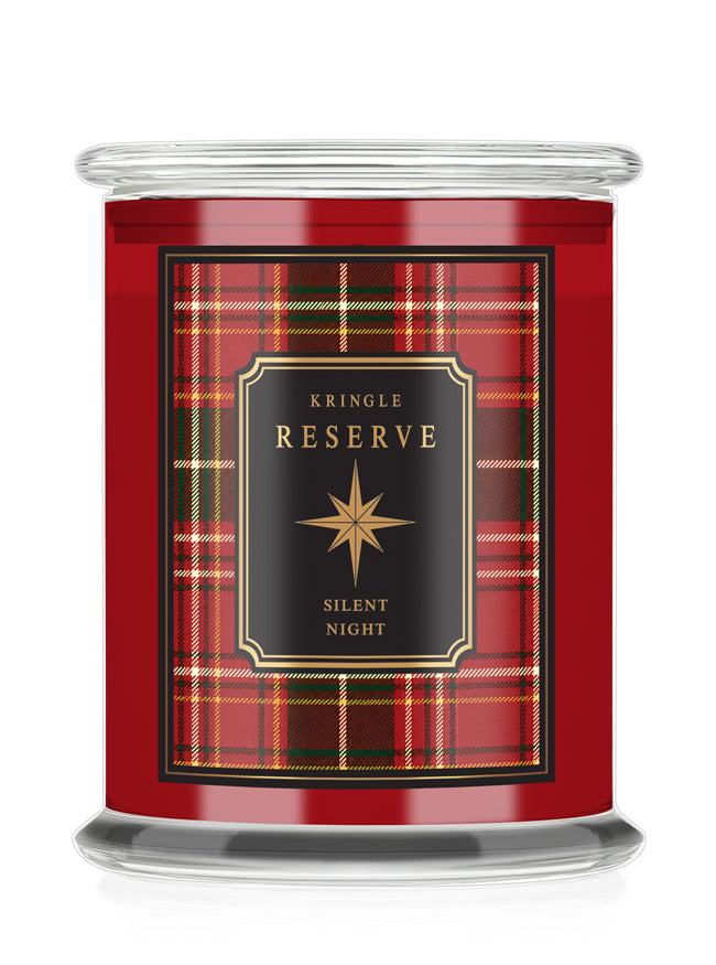 A Kringle Reserve 'Silent Night' scented candle in a  glass jar with a red tartan plaid label featuring a black central panel with gold lettering.