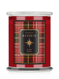 A Kringle Reserve 'Silent Night' scented candle in a  glass jar with a red tartan plaid label featuring a black central panel with gold lettering.