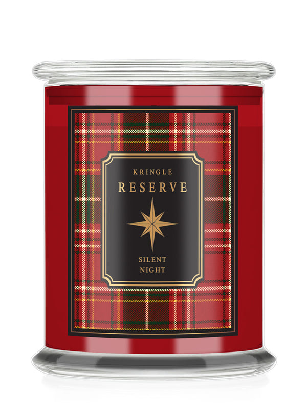 A Kringle Reserve 'Silent Night' scented candle in a  glass jar with a red tartan plaid label featuring a black central panel with gold lettering.