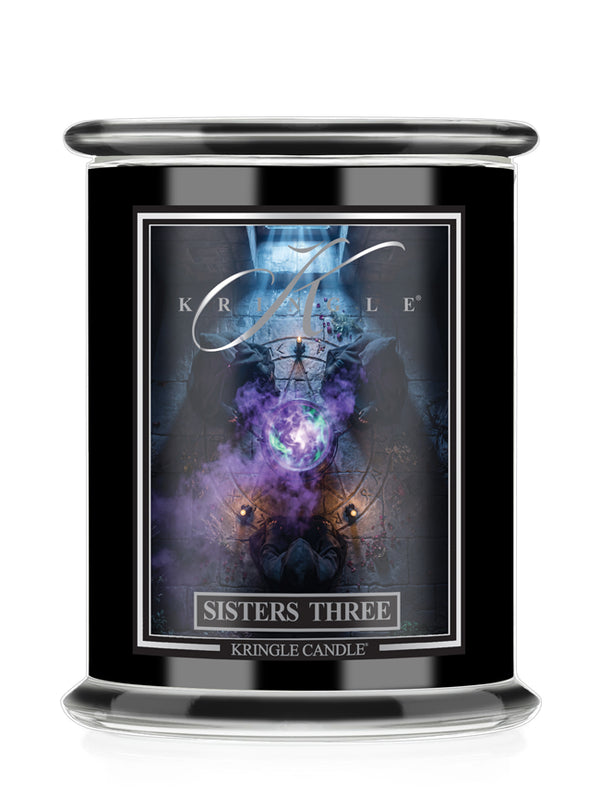 A black glass jar candle  for Kringle Candle's 'Sisters Three' Halloween scent. The label displays a dark, mystical graphic with purple and blue cosmic elements.