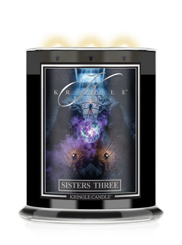 A black glass jar candle  with 3 lit wicks for Kringle Candle's 'Sisters Three' Halloween scent. The label displays a dark, mystical graphic with purple and blue cosmic elements.
