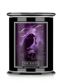 A black glass jar candle featuring a gothic label for 'Kringle Candle' titled 'The Raven'. The label depicts a black raven perched on a skull holding a key in a purple misty graveyard scene.