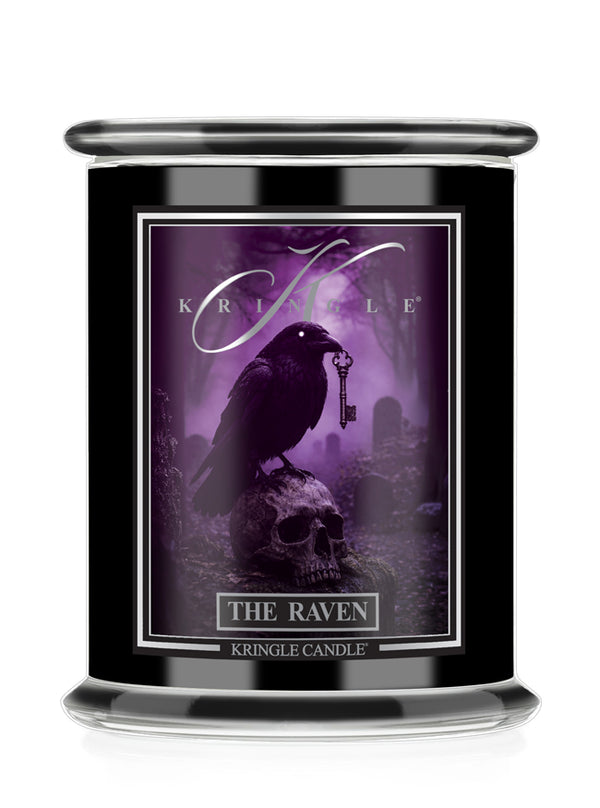 A black glass jar candle featuring a gothic label for 'Kringle Candle' titled 'The Raven'. The label depicts a black raven perched on a skull holding a key in a purple misty graveyard scene.