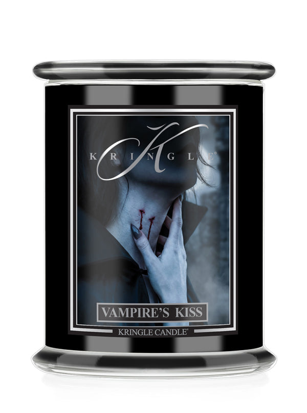 A black glass jar Halloween candle featuring a Halloween-themed label titled 'Vampire's Kiss' by Kringle Candle. The label depicts a pale figure with a hand near their neck with red "bites", set against a dark smoky background.