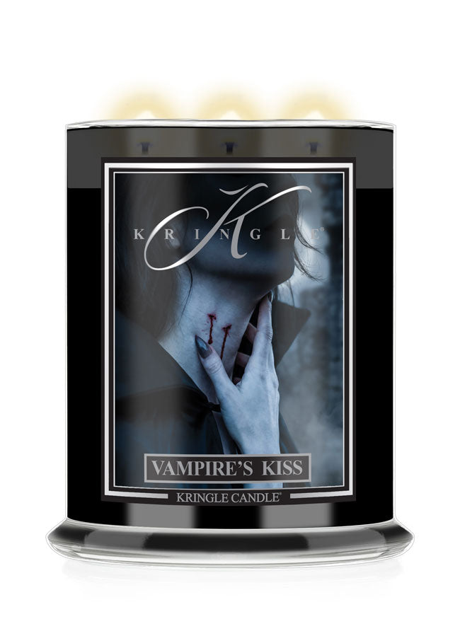 A Kringle Candle jar labeled 'Vampire's Kiss' with a black container, gothic Halloween artwork of a pale hand near a neck, and three glowing wicks at the top on a white background.