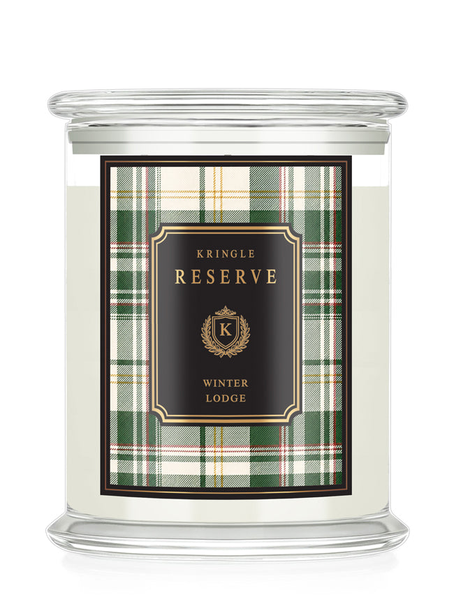 A Kringle Reserve 'Winter Lodge' scented candle in a clear glass jar with a lid, featuring a green and beige plaid label with a black central panel and gold lettering.