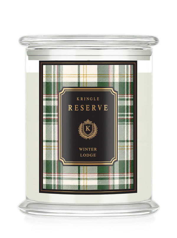A Kringle Reserve 'Winter Lodge' scented candle in a clear glass jar with a lid, featuring a green and beige plaid label with a black central panel and gold lettering.