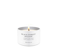 A lit white candle in a white cylindrical tin labeled 'BLACK FOREST BALSAM' with the brand 'KRINGLE' visible, centered on a clean white background.