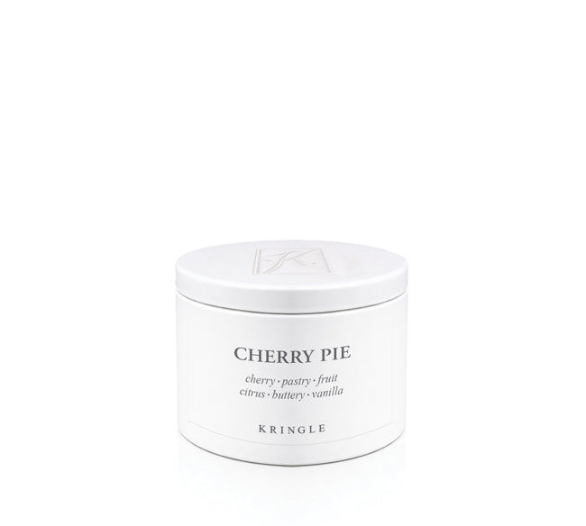 A white round candle tin with a matching lid, labeled 'CHERRY PIE' by the brand KRINGLE, on a seamless white background.