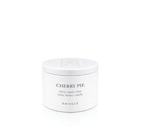 A white round candle tin with a matching lid, labeled 'CHERRY PIE' by the brand KRINGLE, on a seamless white background.