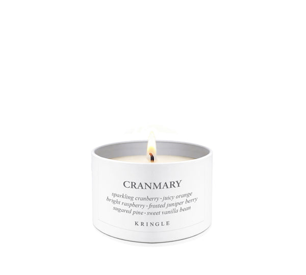 A lit white candle in a white cylindrical tin container with the brand name CRANMARY and the scent name printed on the front, set against a seamless white background.