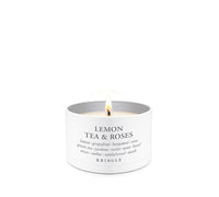 A lit white candle in a white cylindrical tin with the text 'LEMON TEA & ROSES' and the brand 'KRINGLE' printed on the front, set against a solid white background.