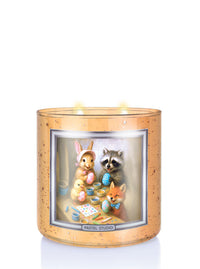 Decorative candle with Easter-themed illustration of animals around a table with art supplies.