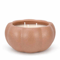 A three-wick candle in a matte, pumpkin-shaped ceramic container with a warm terracotta or light brown finish, set against a plain white background.