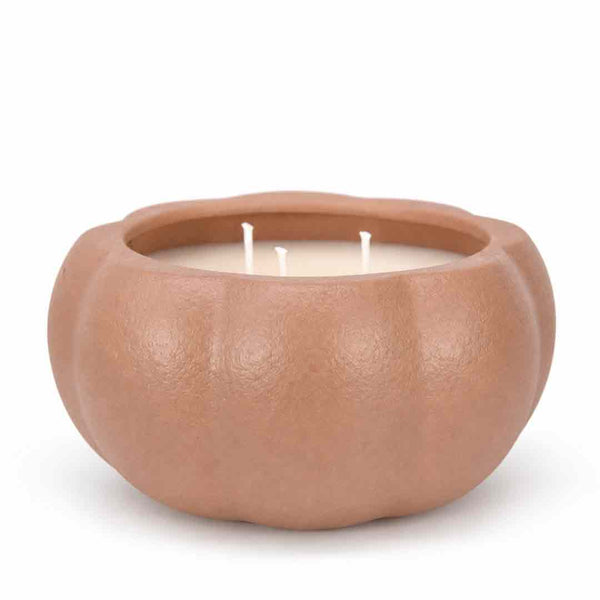 A three-wick candle in a matte, pumpkin-shaped ceramic container with a warm terracotta or light brown finish, set against a plain white background.