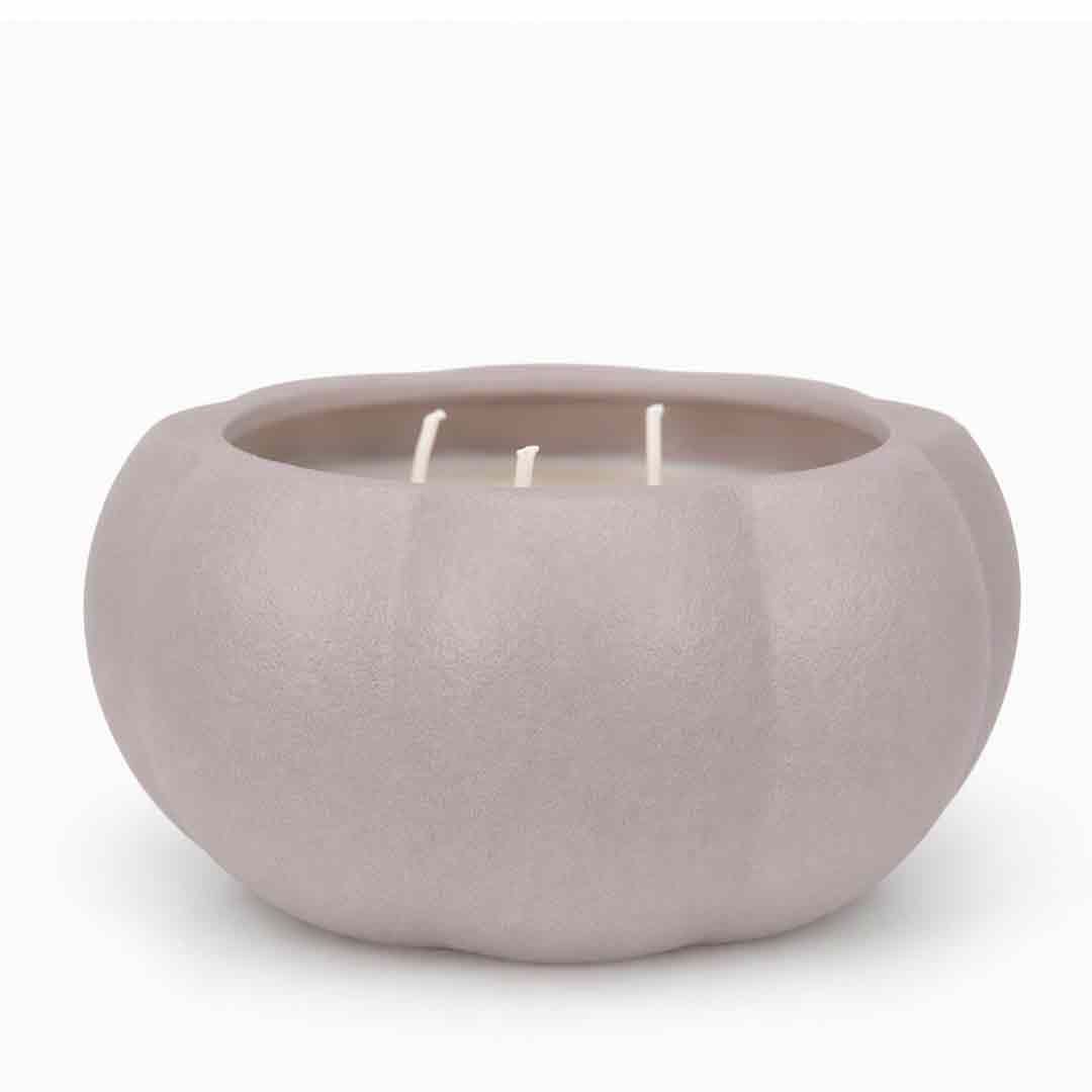 A three-wick candle in a matte, rounded pumpkin-shaped container with a light taupe-gray color, set against a plain white background.