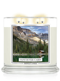 Four-wick candle lit, featuring a scenic label of a lakeside cabin surrounded by trees and mountains,  "Vancouver Cabin"