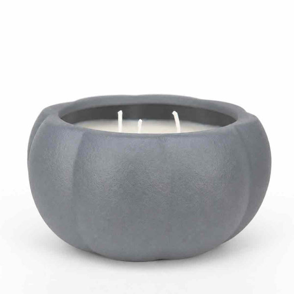 A three-wick candle in a matte gray, pumpkin-shaped ceramic container, photographed on a seamless white background.