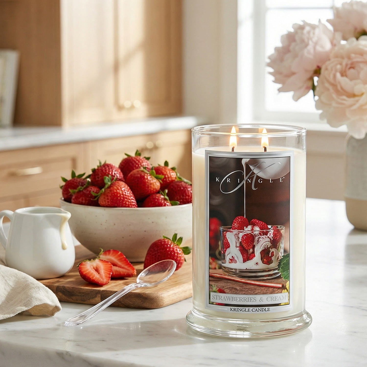 Kriagle strawberry candle on a kitchen counter with strawberries and flowers in the background