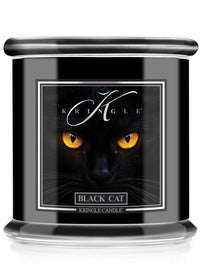 A Kringle Candle jar candle labeled 'Black Cat' featuring a graphic of a black cat's face with glowing yellow eyes on a black container with a silver lid.