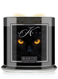 A Kringle Candle jar labeled 'Black Cat' featuring a dramatic graphic of a black cat with glowing yellow eyes on a black background, shown in a clear glass container with a black wax fill.