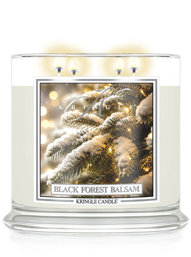 A large Kringle Candle jar labeled 'Black Forest Balsam' with three lit wicks at the top, shown on a clean white background. The front label features a festive image of snow-covered pine branches with warm string lights.