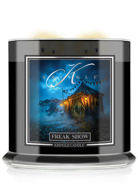 A Halloween Kringle Candle jar candle with a black glass container and a square label featuring a blue-toned circus tent scene and the text 'FREAK SHOW' and 'KRINGLE CANDLE'.