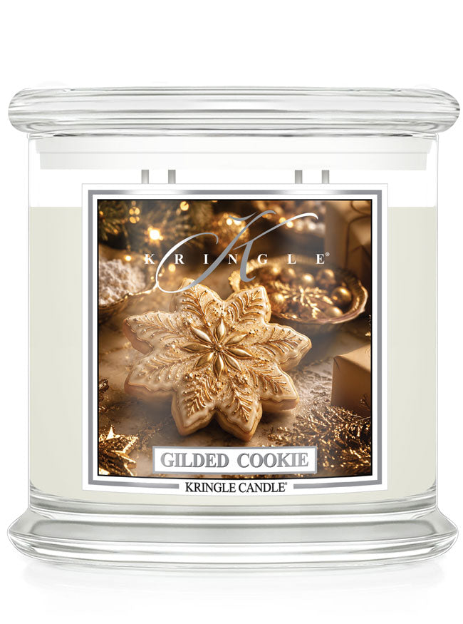 A Kringle Candle in a clear glass jar with white wax, featuring a festive label that reads 'Gilded Cookie' and shows a golden cookie ornament on a warm holiday background.
