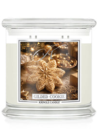 A Kringle Candle in a clear glass jar with white wax, featuring a festive label that reads 'Gilded Cookie' and shows a golden cookie ornament on a warm holiday background.