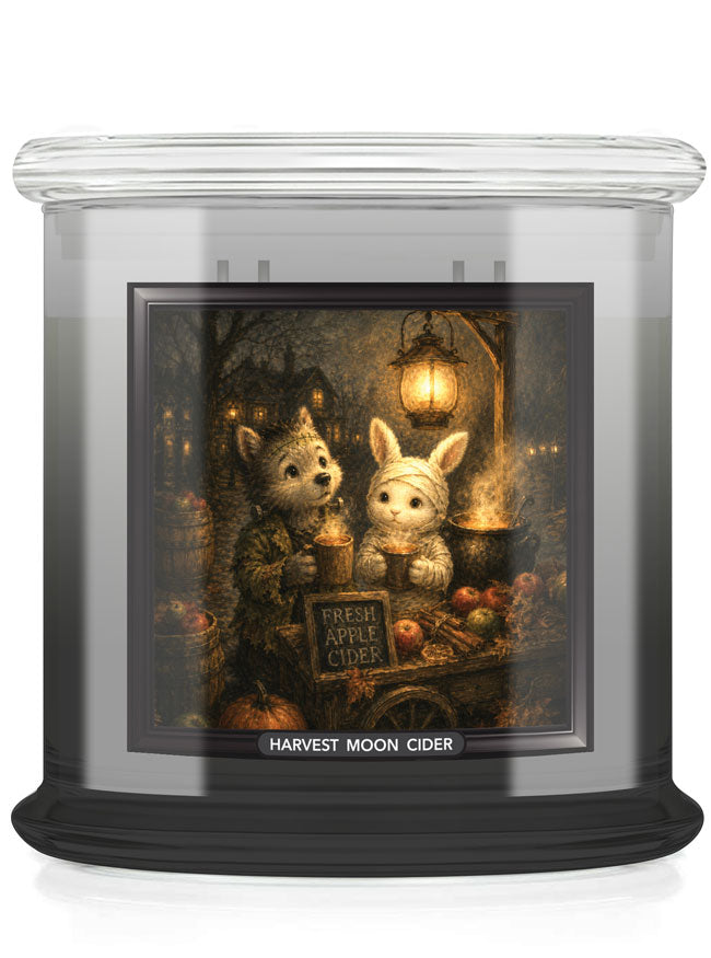 A large glass jar candle with a clear lid and black base, featuring a front label illustration of two cute animals, including a rabbit, at a cider table with the text 'HARVEST MOON CIDER'.