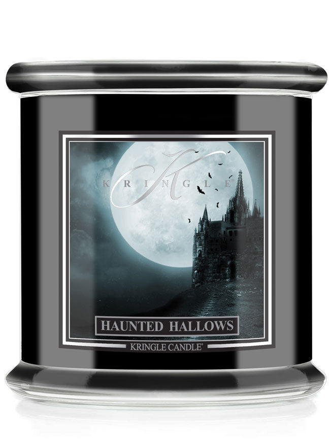 A Kringle Candle jar candle with a black body, featuring a gothic Halloween label that reads 'Haunted Hallows' and shows a haunted house silhouette against a full moon.