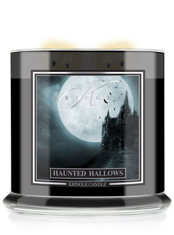 A Kringle Candle jar candle with a black glass container and a front label depicting a spooky gothic castle silhouette against a large full moon, with the text 'Haunted Hallows' and 'Kringle Candle'.