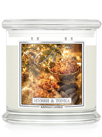 A Kringle Candle jar candle labeled 'Myrrh & Tonka' with a clear glass container, white wax, and a decorative front label showing amber resin, spices, and warm holiday lighting.