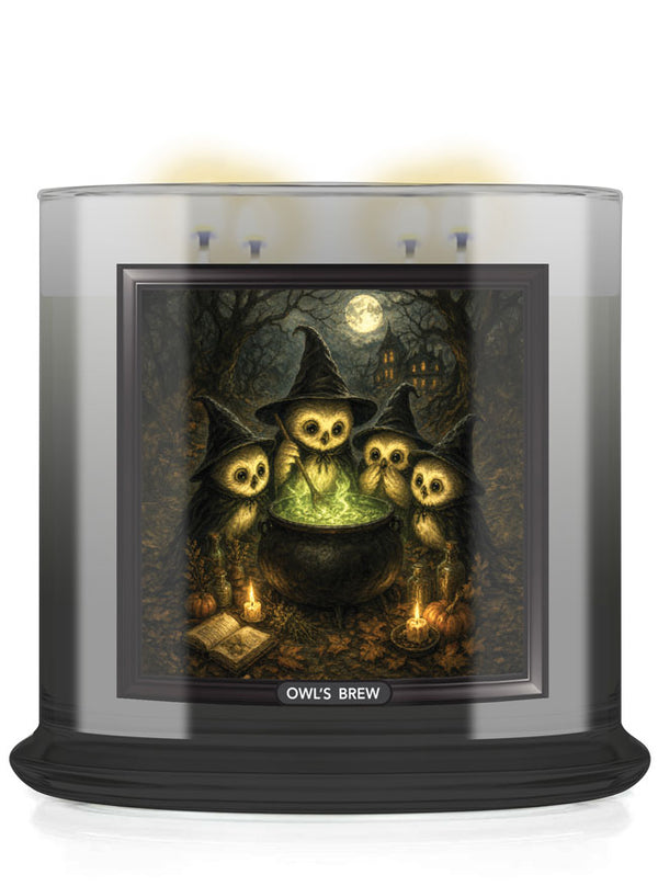 A large scented candle in a clear glass jar with a black base, featuring a Halloween-themed illustration of owl skulls around a cauldron on the front label. The label reads 'OWL'S BREW'.