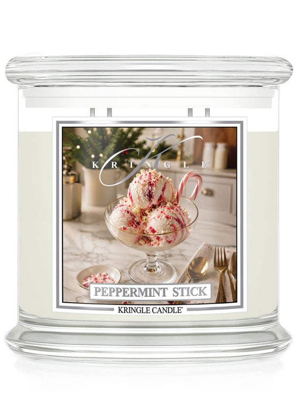 A Kringle Candle jar candle labeled 'Peppermint Stick' with a clear glass container, white wax, and a front label showing a dessert scene with candy canes and peppermint sprinkles.