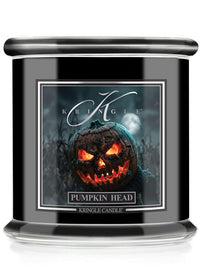 A Kringle Candle in a black glass jar featuring a Halloween-themed label that reads 'Pumpkin Head' with an illustration of a glowing jack-o'-lantern.