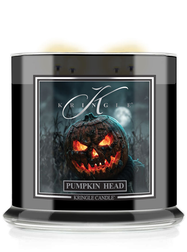 A Kringle Candle in a black glass jar with a Halloween-themed label featuring a glowing jack-o'-lantern pumpkin. The label reads 'KRINGLE' and 'PUMPKIN HEAD'.