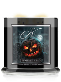A Kringle Candle in a black glass jar with a Halloween-themed label featuring a glowing jack-o'-lantern pumpkin. The label reads 'KRINGLE' and 'PUMPKIN HEAD'.