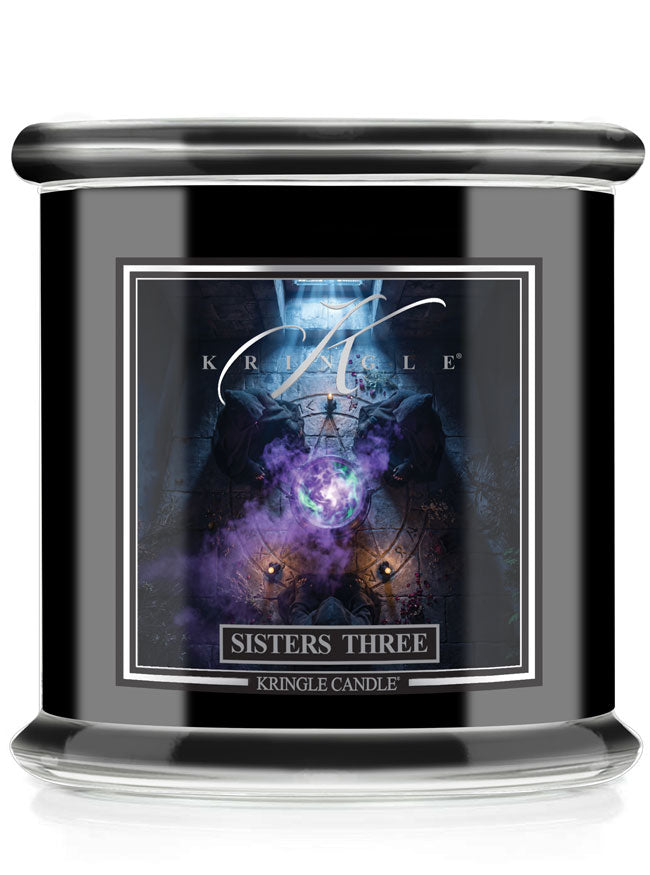 A black glass jar candle with a front label reading 'SISTERS THREE' and 'KRINGLE CANDLE,' featuring for Halloween a dark fantasy illustration with purple and blue light effects.