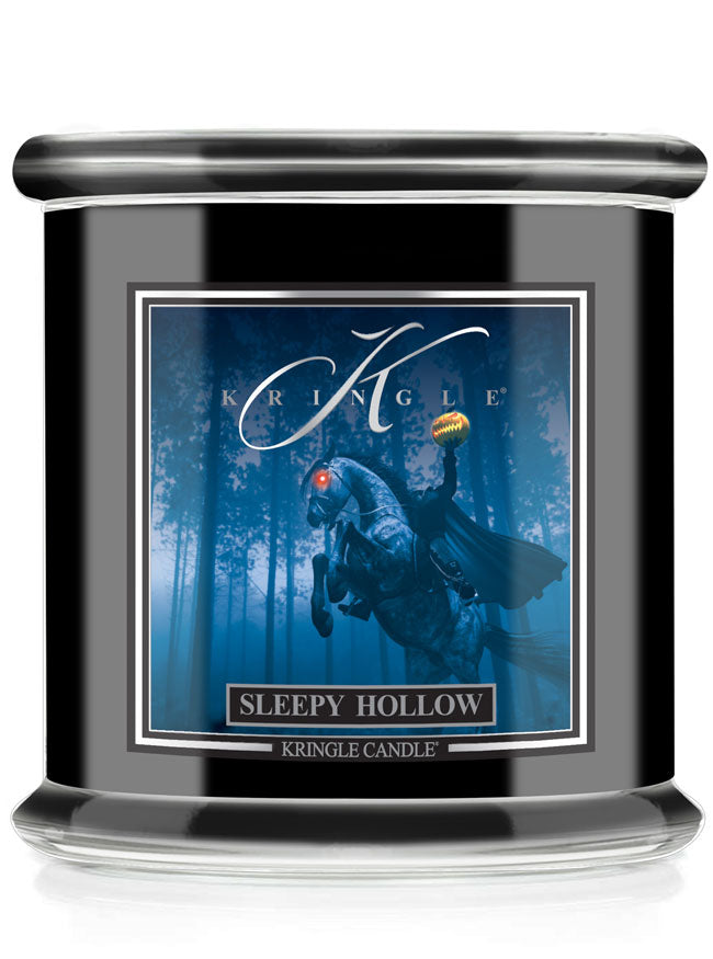 A Kringle Candle in a black glass jar with a silver lid, featuring a front label for 'Sleepy Hollow' with a blue illustration of a ghostly figure and the title.