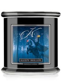 A Kringle Candle in a black glass jar with a silver lid, featuring a front label for 'Sleepy Hollow' with a blue illustration of a ghostly figure and the title.