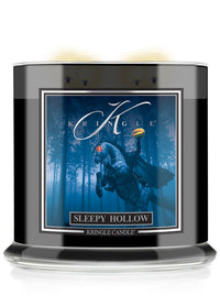 A Kringle Candle in a black glass jar with a dark label featuring a blue-toned illustration of a cloaked figure in a forest and the text 'Sleepy Hollow.'.
