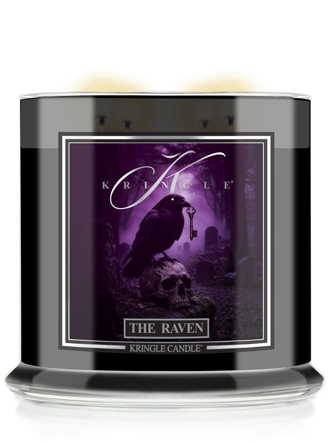 A Kringle Candle jar candle labeled 'The Raven' featuring a Halloween gothic illustration of a raven perched on a skull in a purple misty forest.
