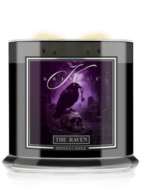 A Kringle Candle jar candle labeled 'The Raven' featuring a Halloween gothic illustration of a raven perched on a skull in a purple misty forest.